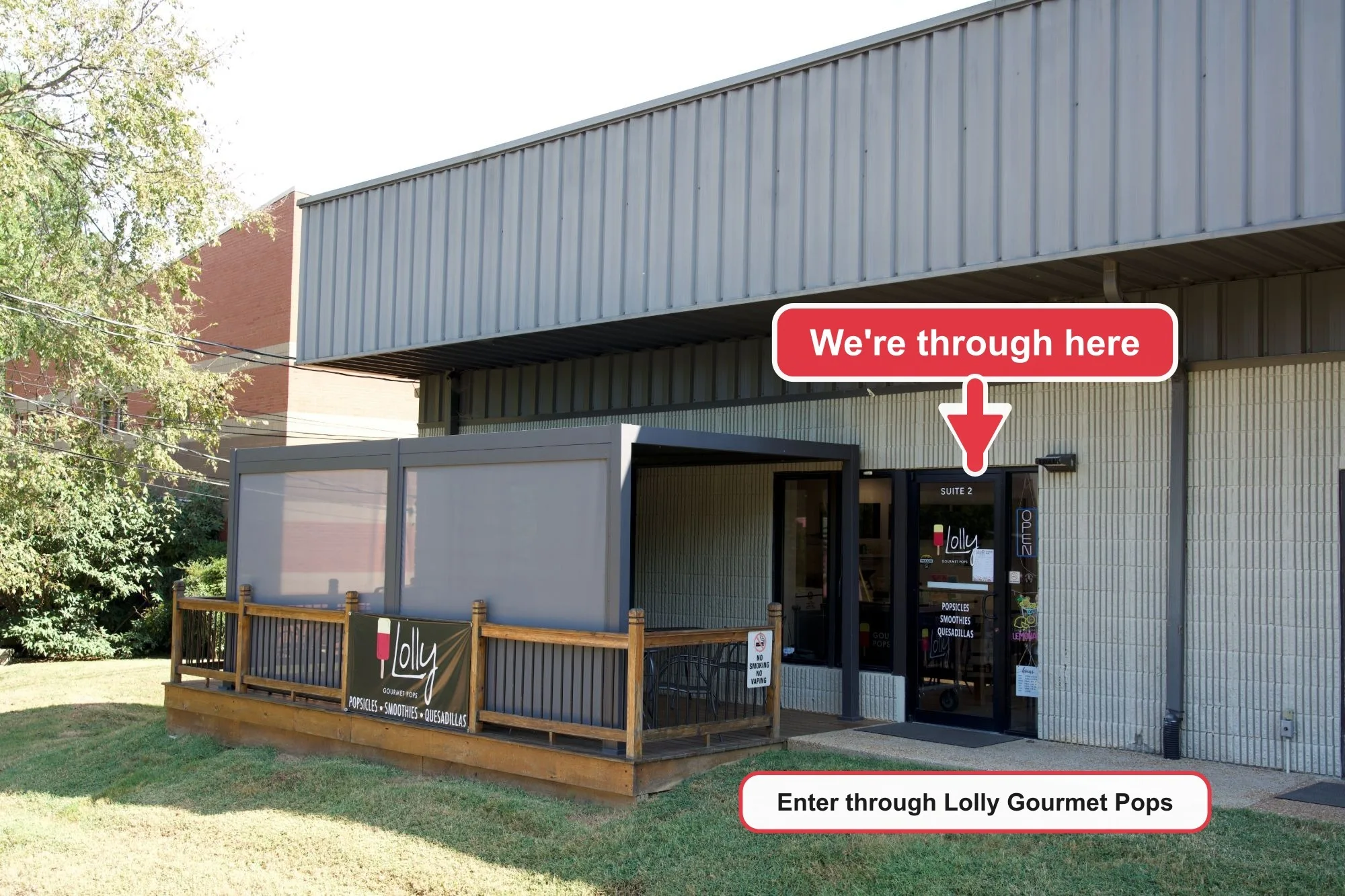 The Lolly Gourmet Pops entrance, a glass door marked Suite 2 next to a wooden deck. An arrow points at the door, marked "We're through here, enter through Lolly Gourmet Pops".