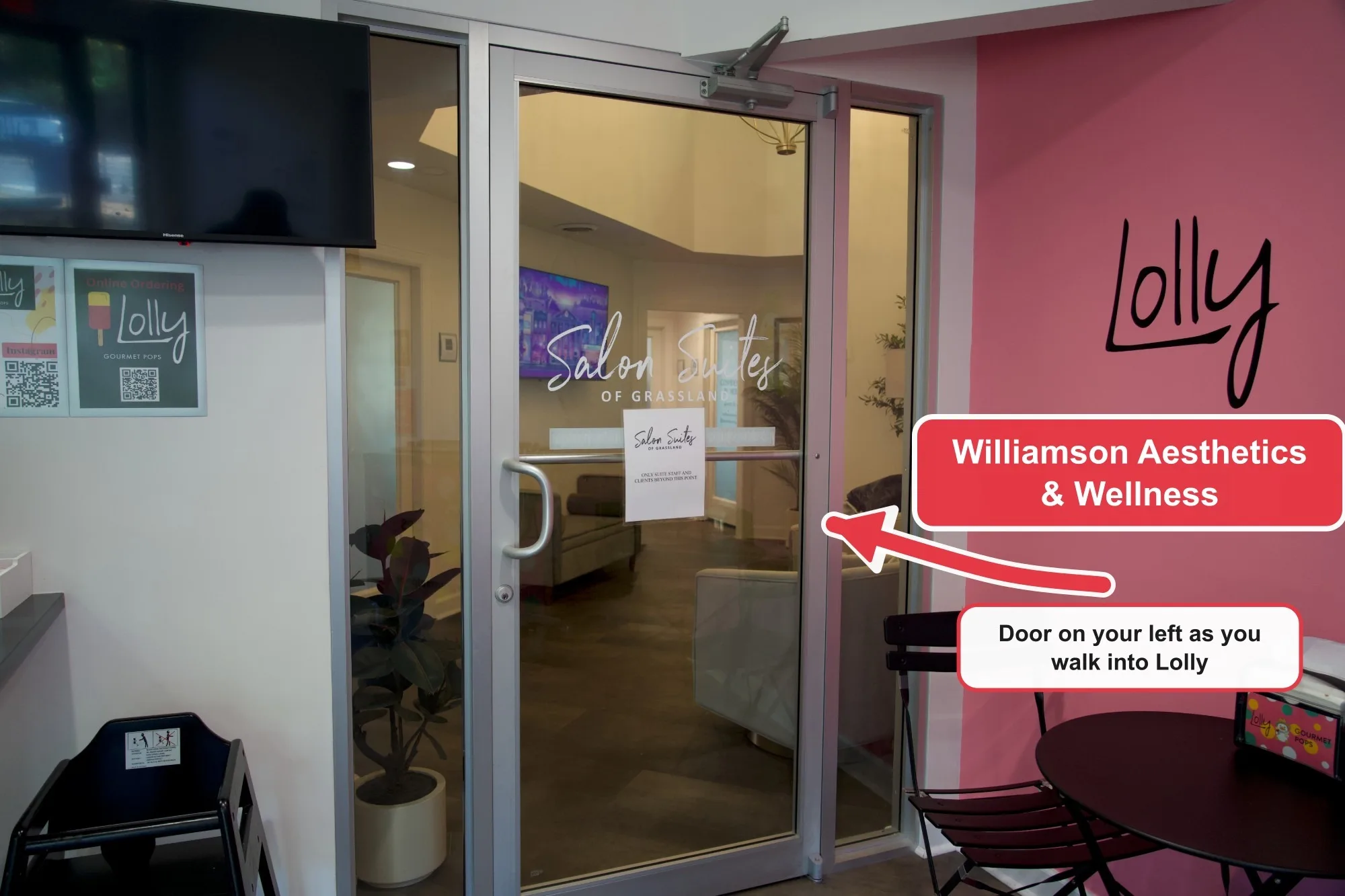 Inside Lolly Gourmet Pops, a glass door with "Salon Suites of Grassland" on it. An arrow points at the door, labeled "Williamson Aesthetics & Wellness, door on your left as you walk into Lolly".